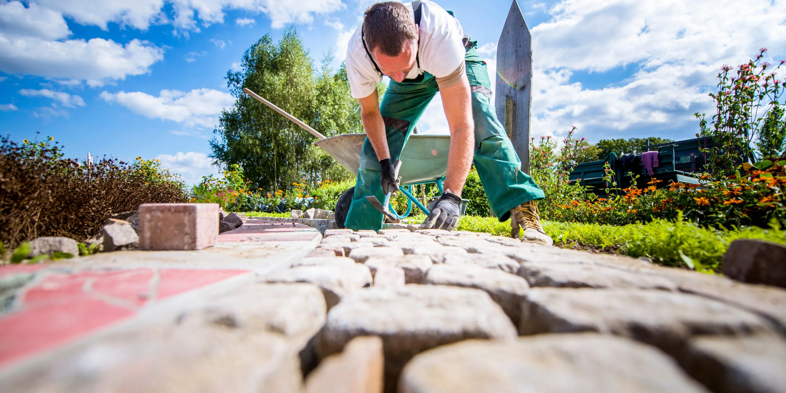 Handwerker verlegt Pflastersteine in einer Gartenanlage