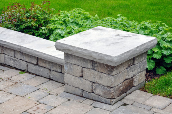 A seat wall with pillars and natural stone coping helps define a
