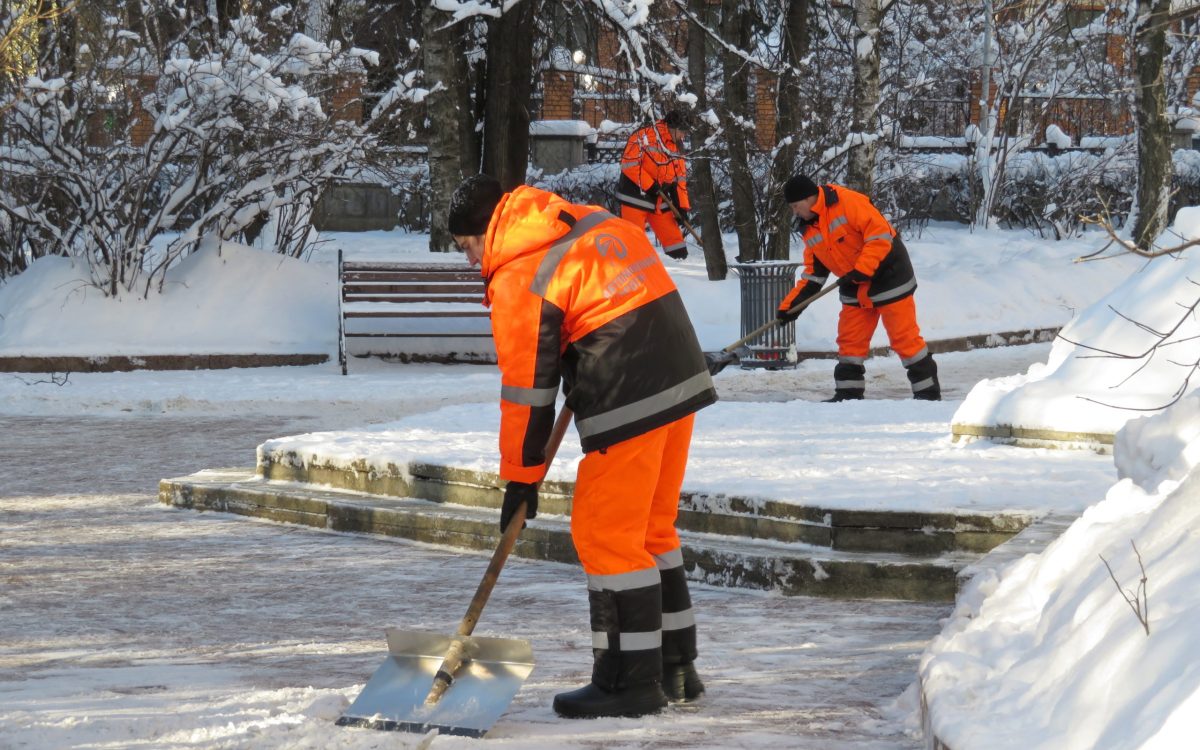 Snow removal in Moscow. Communal services workers in uniform wit