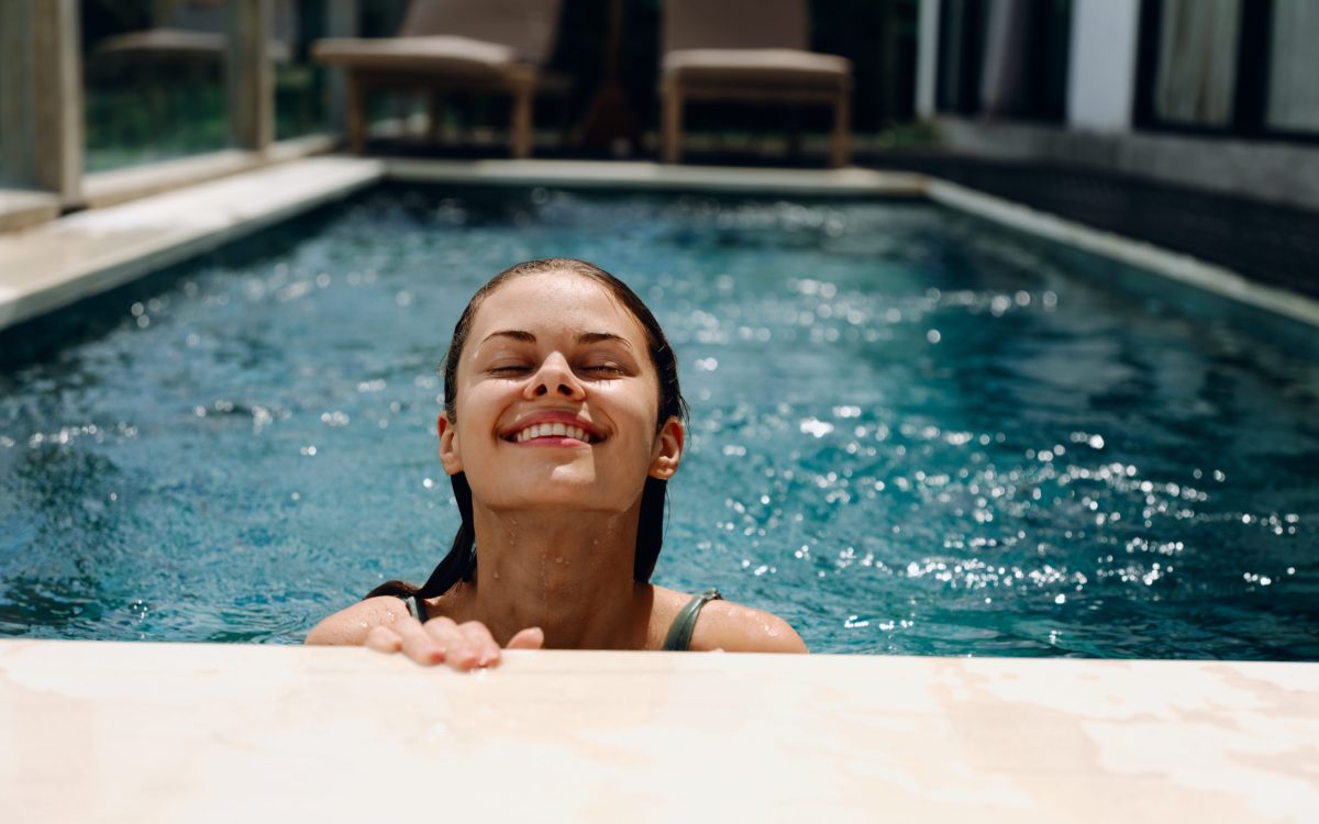 Portrait of a woman with closed eyes smile with teeth floats in the water in the pool in a swimsuit, summer vacation, vacation and travel to the tropics, beach lifestyle. High quality photo
